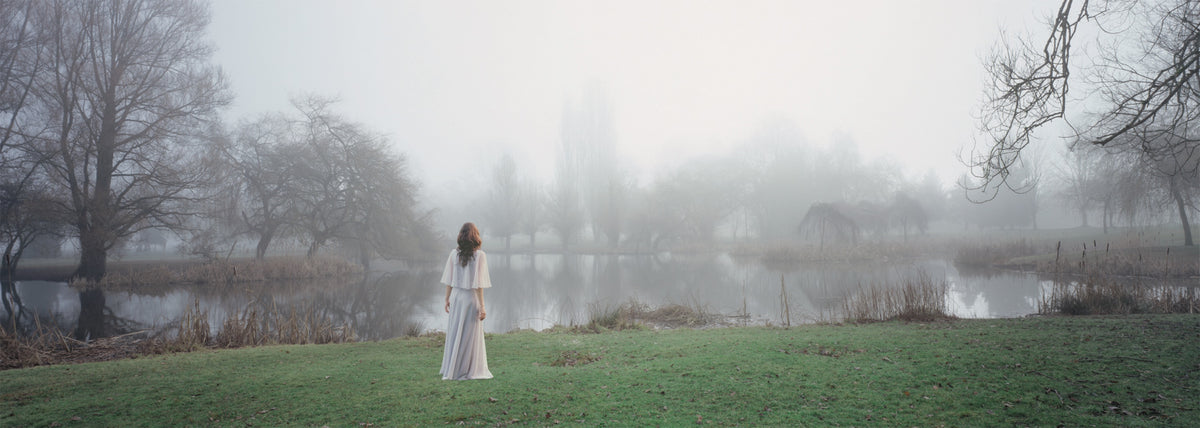 Karin Bubaš, Mystic, 2008. Photograph of a woman in white on a lush green hill looking at something in the horizon on foggy day.