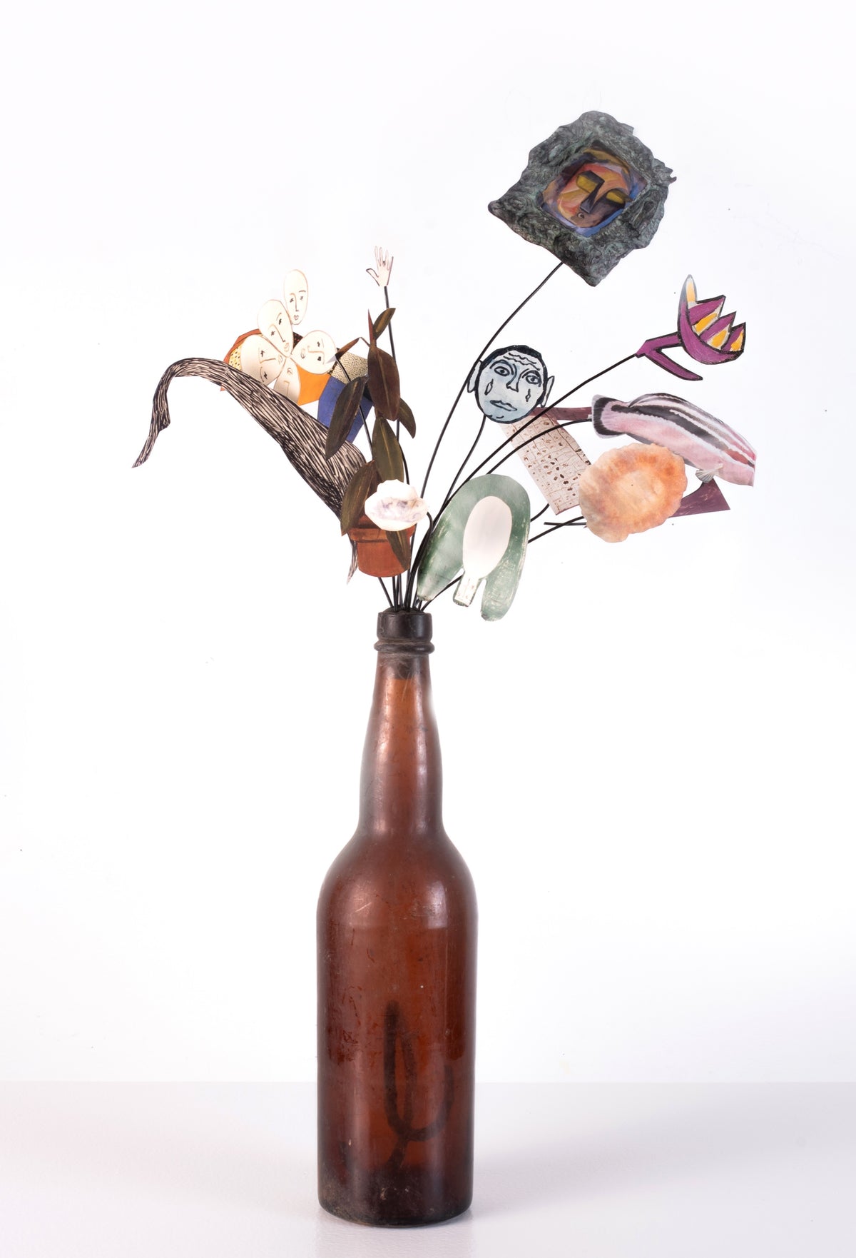 Geoffrey Farmer, Bouquet, 2003. An old glass bottle with paper objects, attached on a black wires, coming out of the bottle.