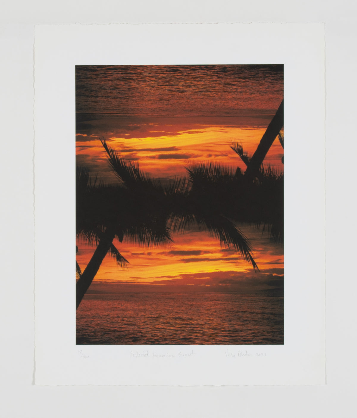 Vikky Alexander, Reflected Hawaiian Sunset, 2021. Print of a vivid tropical sunset with silhouetted palm trees mirrored to create a symmetrical reflection. The sky glows with rich hues of orange, red, and yellow.