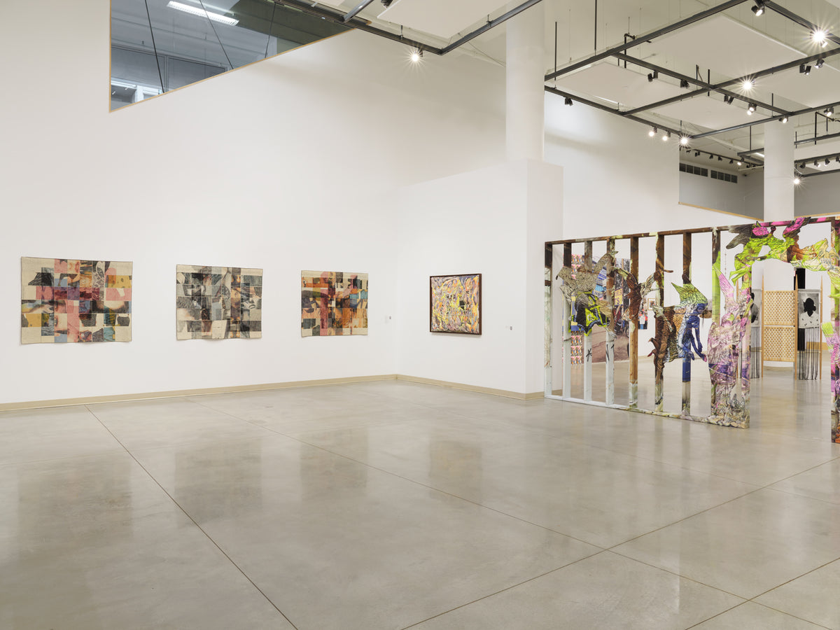 Three patchwork textile pieces and a framed work hang beside a freestanding wooden frame covered in colourful cut-out figures