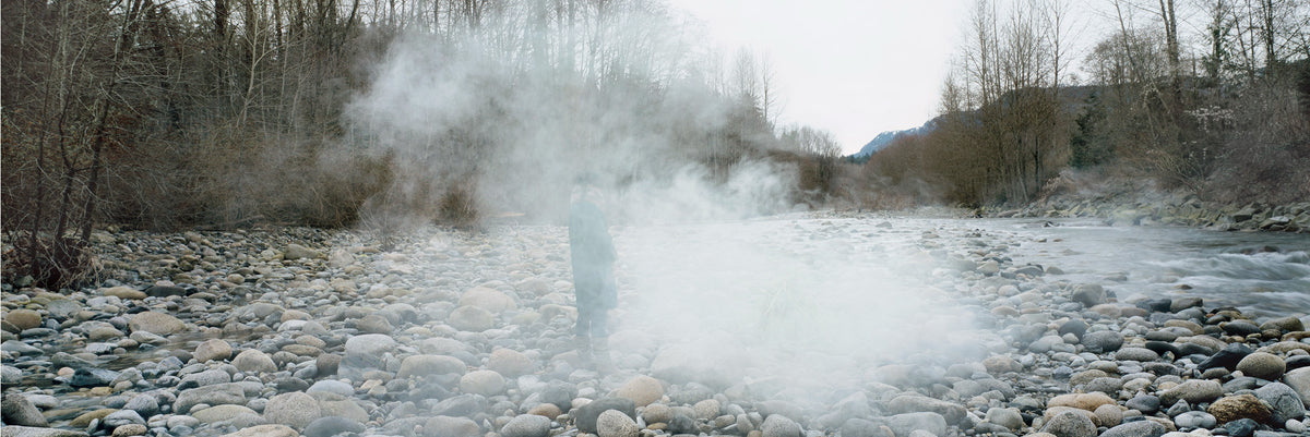 Karin Bubaš, Late Winter, Lynn Creek, 2010. Rocky and foggy landscape by a body of water with a figure within the fog.